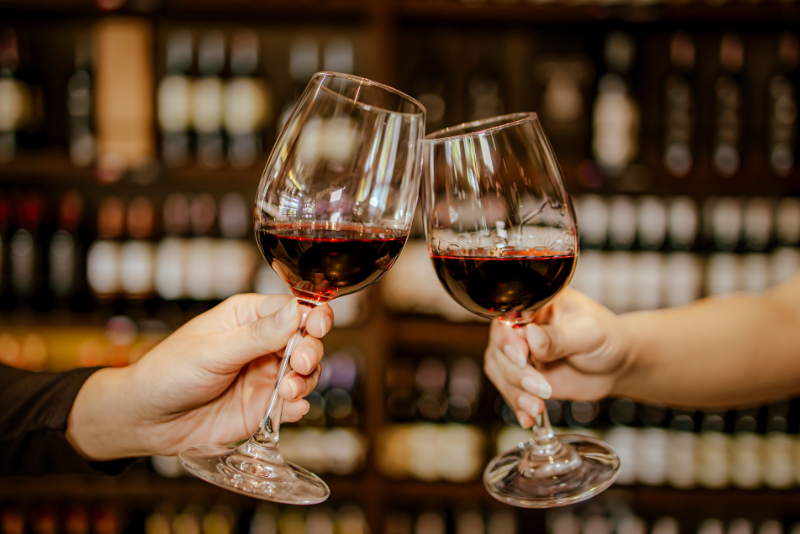 two people clinking glasses filled with red wine