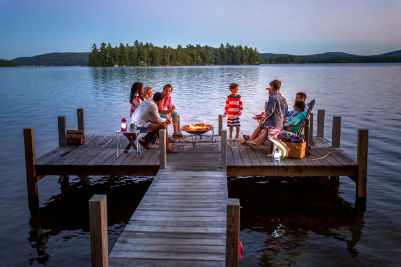 group gathered at the end of a dock at nighttime over the lake