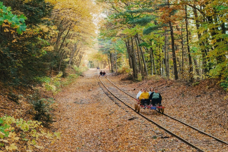 group using a four person rail bike with orange leaves on the ground in new hampshire