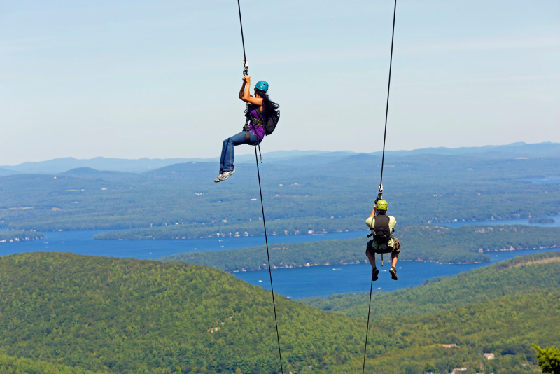 two people on ziplines above mountains and lakes