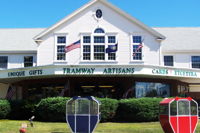 facade and exterior of tramway artisans gift shop, with one blue and one red tram on a grass lawn