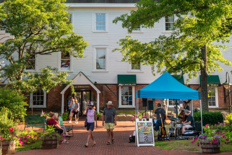 brick walkway surrounded by lush trees and a tent at the outside of the mill falls marketplace in new hampshire
