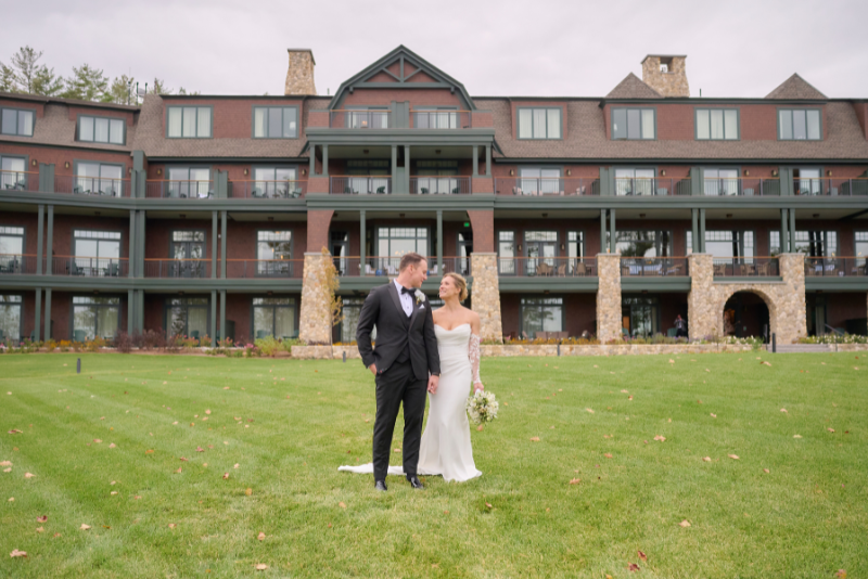 bride and groom posing on green lawn at the lake estate on winnisquam