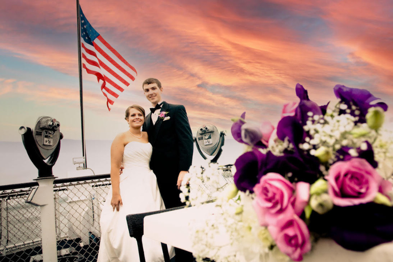 bride and groom pose against pink sky sunset, american flag, and flowers on a cruise
