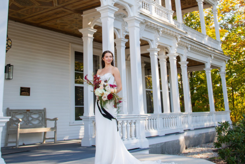 bride poses with flowers on porch outside tilton mansion